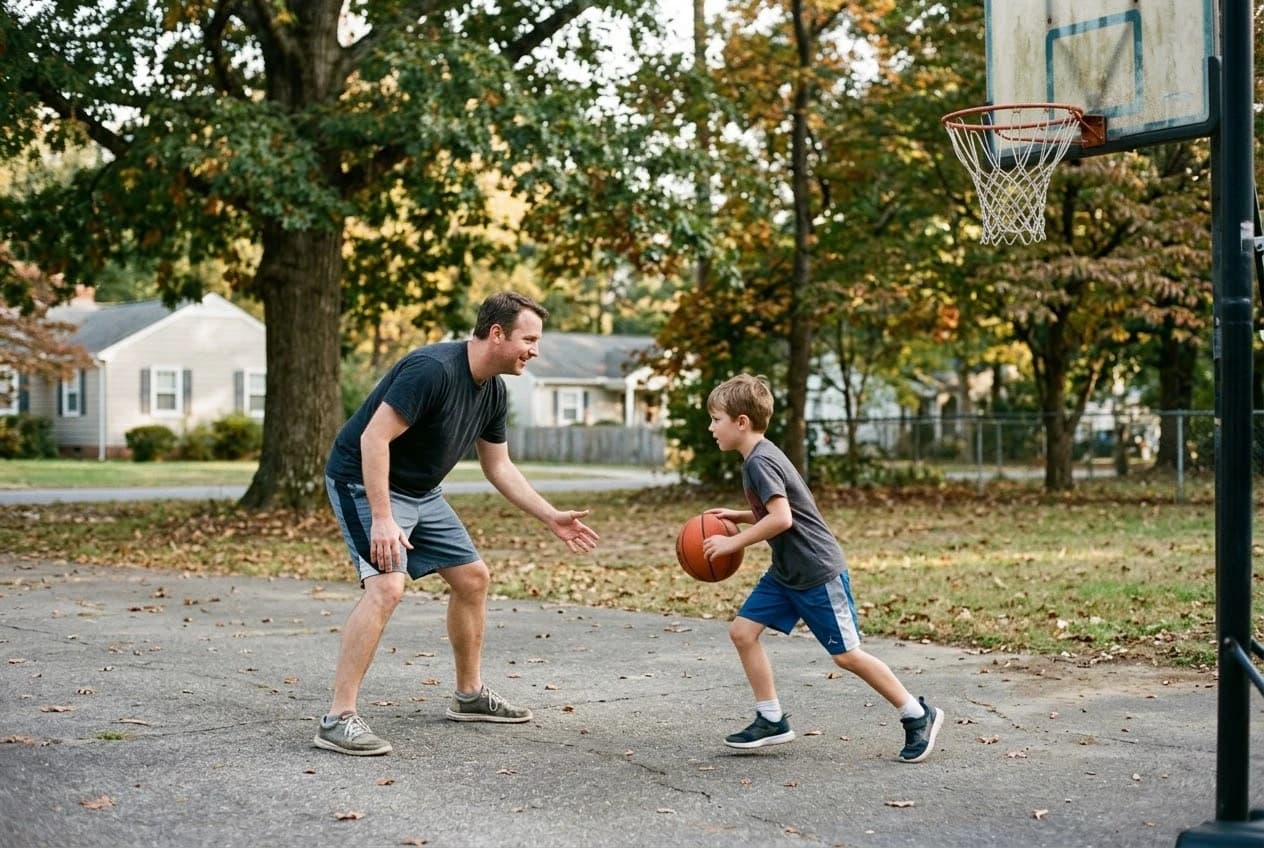 A father and son playing basketball in a neighborhood driveway.